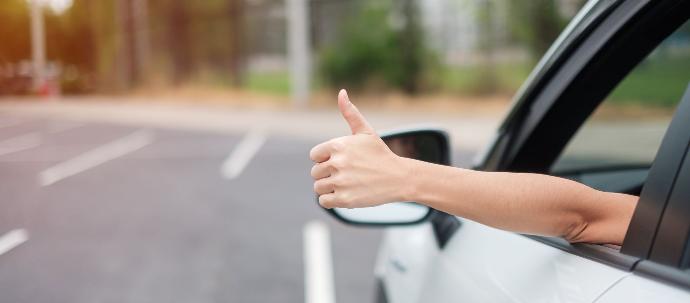 Prórrogas Conductora levantando el dedo de manera positiva por fuera de la ventana mientras está dentro del coche