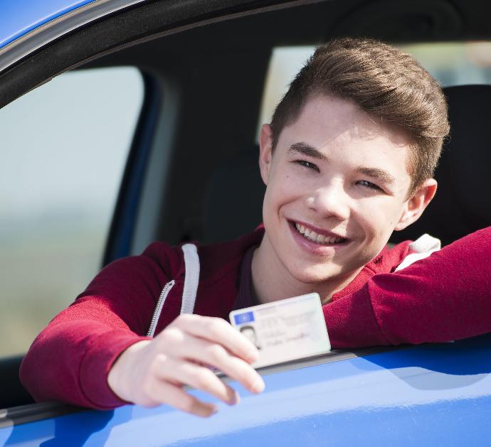 Canjes Joven conductor mostrando su carné en su coche azul