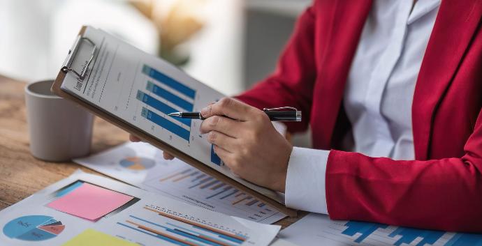 Estados financieros Mujer en traje rojo enseñando gráficos en papeles