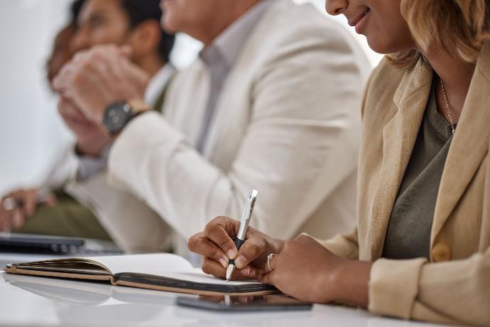 Actas de junta y consejo Mujer en reunión apuntando en libreta