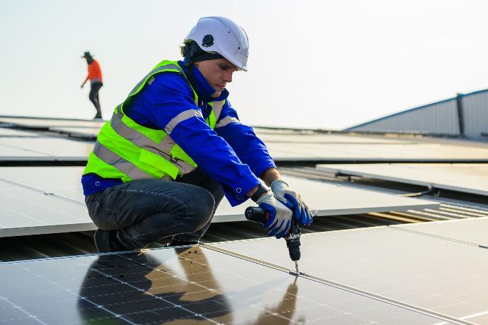 Subvenciones para el autoconsumo Trabajador colocando una placa fotovoltaica en un tejado