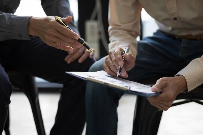 Informe de vehículos Personas debatiendo sobre la firma de documentos mientras ambos sujetan un bolígrafo
